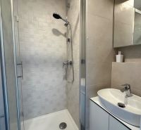 Duschkabine mit Keramikfliesen im Badezimmer des Einzimmerapartments.
