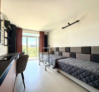 Einzimmerwohnung mit zwei Betten, einem Tisch und einem Blick durch ein großes Fenster.