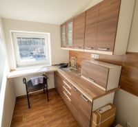 Küche mit Schränken in Holzoptik und Tisch, Besondere Immobilien.