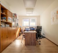 Ein Büro mit einem Tisch, Stühlen, einem Schrank und einem Boden mit Holzdekor. Besondere Immobilien.