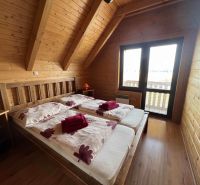 Eine Hütte mit einem Doppelbett, Holzboden, großes Fenster mit Aussicht.