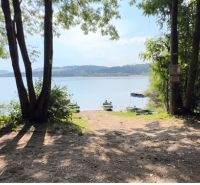 Ein See, umgeben von Bäumen, bei einer Hütte in Liptovská Sielnica, Boote auf dem Wasser.