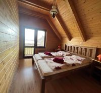 Eine Hütte mit einem Boden in Holzoptik, Holzwänden, einem Doppelbett, Nachttischen, einer Lampe.