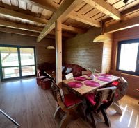 Das Innere der Hütte mit Holzeinrichtung und einem großen Esstisch mit roten Kissen.