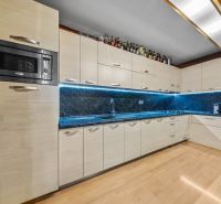 Küche in einem Einfamilienhaus mit Holzboden, eingebauten Geräten und LED-Beleuchtung.