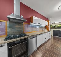 Küche eines Einfamilienhauses mit roter Wand, modernen Geräten und Holzboden.