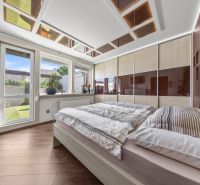 Schlafzimmer mit Holzboden, Kleiderschrank und großem Fenster in einem Einfamilienhaus.
