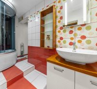 Ein Badezimmer in einem Einfamilienhaus mit bunten Fliesen, einer Duschkabine und einem Waschbecken.