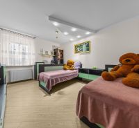 Kinderzimmer in einem Einfamilienhaus mit zwei Betten, Plüschbären und einem Boden in Holzoptik.