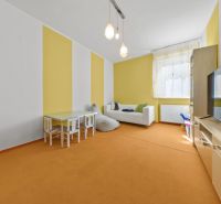 Wohnzimmer mit farbigen Wänden, Sofa, Fernseher und Kindertisch in einem Einfamilienhaus.