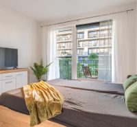 Schlafzimmer in einer Einzimmerwohnung mit Fernseher, Spiegeln und Balkon, Boden mit Holzdekor.