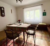 Esszimmer in einem Einfamilienhaus mit einfacher Einrichtung, Uhr und Kreuz an der Wand.