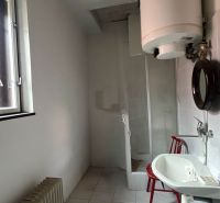 Badezimmer in einem Einfamilienhaus mit Fenster, Waschbecken und Wassererhitzer.