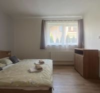 Einfach eingerichtetes Schlafzimmer mit Bett und Boden in Holzoptik in einer 2-Zimmer-Wohnung.