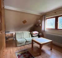 Innenraum eines Einfamilienhauses mit Sofa, Tisch und Boden in Holzoptik.