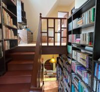 Eine Treppe und Bücherregale voller Bücher in einem Einfamilienhaus mit einem Boden in Holzoptik.