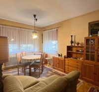 Wohnzimmer in einem Einfamilienhaus mit einer Wohnwand aus Holz, einem Sofa und einem Esstisch.