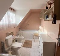 Badezimmer im Einfamilienhaus mit Badewanne, Waschbecken, Toilette und weißen Fliesen.