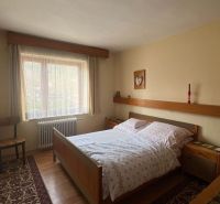 Schlafzimmer in einem Einfamilienhaus mit Bett, Stuhl, Teppich und Holzboden.
