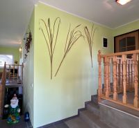 Ein hellgrüner Flur mit einem Holzgeländer, einem Tisch und einer Wanddekoration in einem Einfamilienhaus.