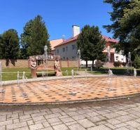 Brunnen und Bank mit geschnitzten Figuren im Dorf Polomka.
