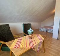 Wohnbereich eines Einfamilienhauses mit Holzboden und einfacher Sitzgelegenheit.