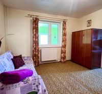 Einfamilienhaus: Zimmer mit Teppich, Sofa, Fenster und Schrank, Durchgang zum Schlafzimmer.