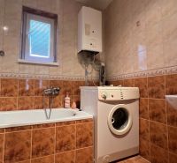 Badezimmer im Einfamilienhaus mit Badewanne, Waschmaschine und Gaskessel.