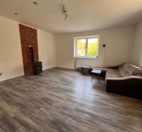 Wohnzimmer in einem Einfamilienhaus mit Holzboden, Kamin und Sofa.