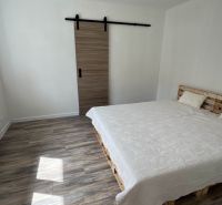 Schlafzimmer in einem Einfamilienhaus mit Palettenbett, Schiebetüren und Boden mit Holzdekor.