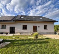 Ein Einfamilienhaus in Krmeš in Liptovský Mikuláš mit Solarpanelen und einem gepflegten Vorgarten.