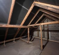 Dachboden eines Einfamilienhauses mit Holzbalken und unverputzten Wänden.