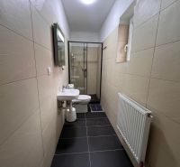 Ein Badezimmer in einem Einfamilienhaus mit Fliesen, Waschbecken und Duschkabine.