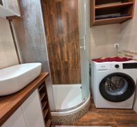 Badezimmer in einer 2-Zimmer-Wohnung mit Waschmaschine und Boden in Holzoptik.