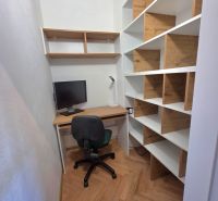 Arbeitsbereich mit Holzboden und Regalen in einer Zweizimmerwohnung.