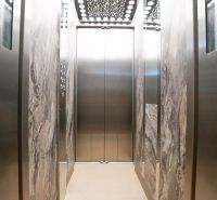 Interieur eines Aufzugs mit Marmorverkleidung und verspiegelten Wänden.