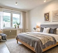 Helles Schlafzimmer mit Einrichtung in einer 2-Zimmer-Wohnung, Bett, Sessel, Pflanzen.