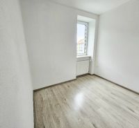 Ein Zimmer in einer Einzimmerwohnung mit einem Boden in Holzoptik und einer hellen Wand.