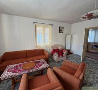 Wohnzimmer in einem Einfamilienhaus mit einem orangefarbenen Sofa und einem gemusterten Teppich.