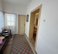 Chodba in einem Einfamilienhaus mit gefliestem Boden, weißen Wänden und einfacher Einrichtung.