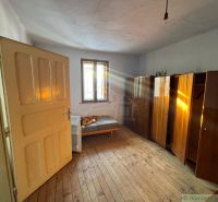 Ein Zimmer in einem Einfamilienhaus mit einem Boden in Holzoptik und einfacher Einrichtung.