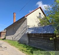 Ein Einfamilienhaus in Šumiac mit einem Blechdach, angrenzend an die grüne Natur und die Straße.
