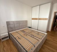 Schlafzimmer mit Bett, Schrank und Holzboden in einer 2-Zimmer-Wohnung.