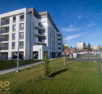 Ein Wohnhaus in Poprad mit grünem Rasen und benachbarten Gebäuden im Hintergrund.
