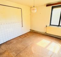 Ein unmöbliertes Zimmer mit Fenster, Heizkörper und einem Boden in Holzoptik in einem Einfamilienhaus.