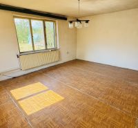 Ein Zimmer mit einem Holzboden, einem großen Fenster und einem Heizkörper in einem Einfamilienhaus.