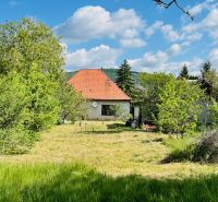 Ein Einfamilienhaus in Pažiti, umgeben von Bäumen und Rasen, mit einem roten Dach.