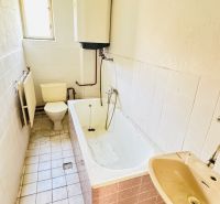 Badezimmer in einem Einfamilienhaus mit Badewanne, Waschbecken und Toilette.