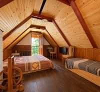 Dachzimmer in der Hütte mit Holzeinrichtung und Bett.