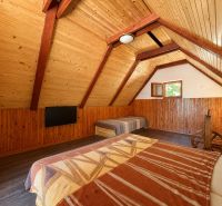Das Dachgeschoss in der Hütte mit Holzeinrichtung bietet ein Bett und einen Fernseher.
